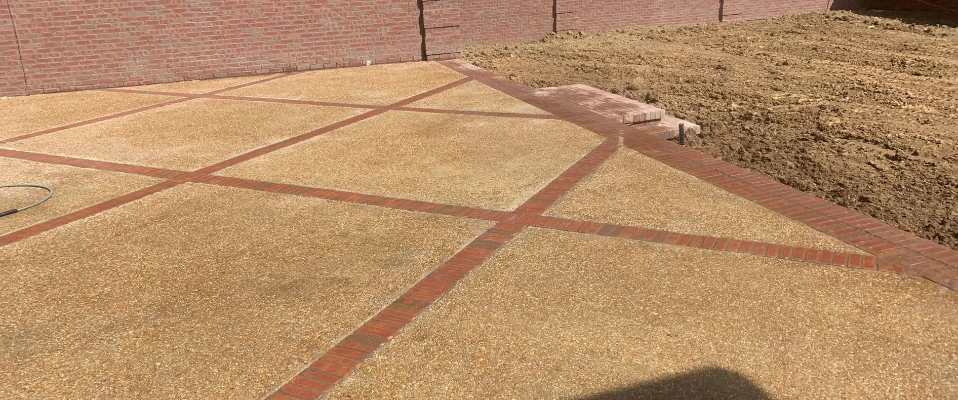 Decorative concrete patio with red brick banding poured by Battle Concrete in North Alabama